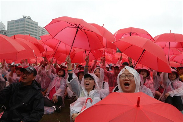 Protesters shout as they hold umbrellas during a rally demanding peace on the Korean peninsula, Seoul, South Korea, Tuesday, Aug. 15, 2017 (AP photo by Lee Jin-man).