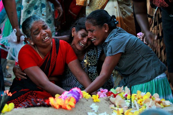 Sri Lankan ethnic Tamil women cry at the graves of relatives who died in fighting between the army and Tamil Tiger rebels, Mullivaikkal, Sri Lanka, May 18, 2015 (AP photo by Eranga Jayawardena).