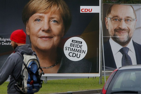 A man walks by campaign posters of German Chancellor Angela Merkel and her main challenger, Martin Schulz, Frankfurt, Germany, Sept. 20, 2017 (AP photo by Michael Probst).