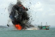 Debris flies into the air as foreign fishing boats are blown up by Indonesia’s navy off Batam Island, Indonesia, Feb. 22, 2016 (AP photo by M. Urip).