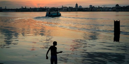 A young man fishes on the shores of Regla as commuters cross the bay by ferry to Havana, March 14, 2016 (AP photo by Ramon Espinosa).