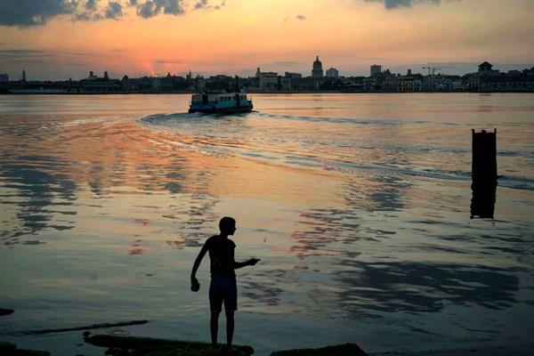 A young man fishes on the shores of Regla as commuters cross the bay by ferry to Havana, March 14, 2016 (AP photo by Ramon Espinosa).