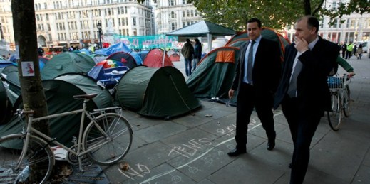 Businessmen walk past tents put up by protesters from the Occupy London Stock Exchange group outside St Paul's Cathedral, London, Oct. 17, 2011 (AP photo by Matt Dunham).