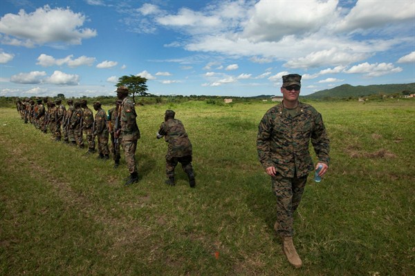 A U.S. Marine major walks past a line of soldiers from the Uganda People’s Defense Force as they engage in weapons training at the Singo facility in Kakola, Uganda, April 30, 2012 (AP photo by Ben Curtis).