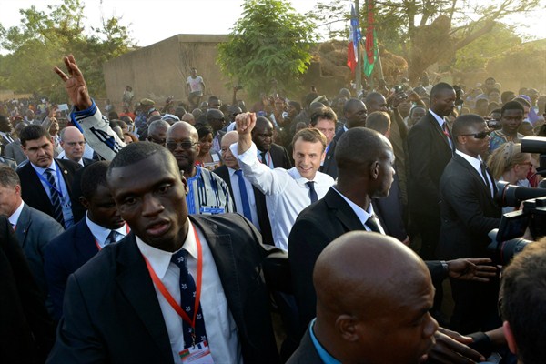 French President Emmanuel Macron, center right, and Burkina Faso’s president, Roch Marc Christian Kabore, center left, wave during a visit to a school in Ouagadougou, Burkina Faso, Nov. 28 , 2017 (AP photo by Ahmed Yempabou Ouoba).