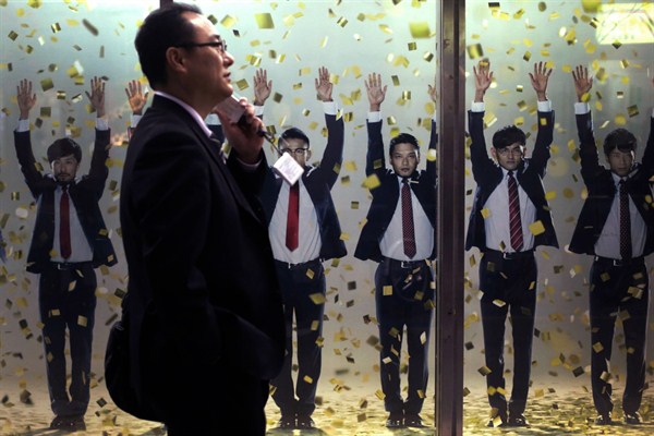 A Japanese businessman walks past an advertisement of a Japanese suit retailer in Tokyo, March 19, 2014 (AP photo by Eugene Hoshiko).