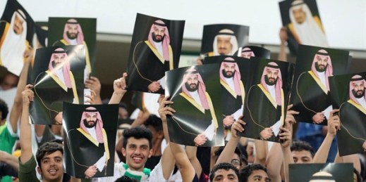 Soccer fans in Saudi Arabia cheer as they hold up pictures of King Salman and Crown Prince Mohammed bin Salman during a 2018 World Cup qualifying match in Jiddah, Saudi Arabia, Sept. 5, 2017 (AP photo).