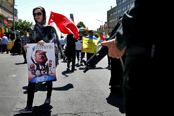 An Iranian holds a poster showing caricatures of U.S. President Donald Trump,  Israeli Prime Minister Benjamin Netanyahu and Saudi Arabia's King Salman, Tehran, Iran, June 23, 2017 (AP photo by Ebrahim Noroozi).