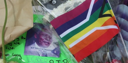 A flag of the South African LGBT community sits next to a portrait of former South African President Nelson Mandela and other mementos, Johannesburg, South Africa, Dec. 7, 2013 (AP photo by Tsvangirayi Mukwazhi).