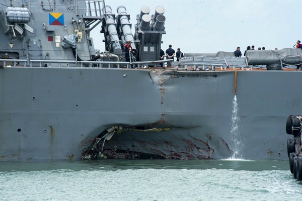 Damage to the portside is visible as the USS John S. McCain steers toward a naval base in Singapore following a collision, Aug. 21, 2017 (U.S. Navy photo via AP).