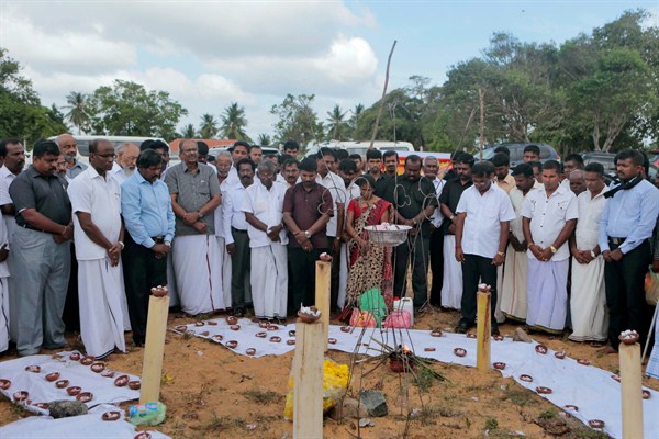 Sri Lankan Tamil activists observe a moment of silence near a makeshift monument where thousands were killed in fighting between the army and Tamil Tiger rebels, Mullivaikkal, Sri Lanka, May 18, 2015 (AP photo by Eranga Jayawardena).