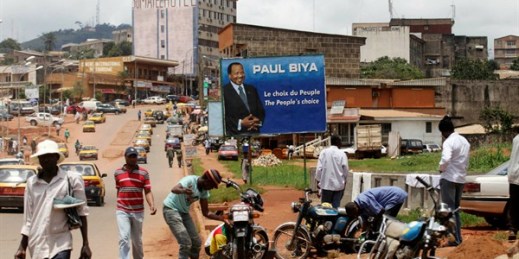 People walk past a campaign billboard for President Paul Biya, Yaounde, Cameroon, Oct. 7, 2011 (AP photo by Sunday Alamba).
