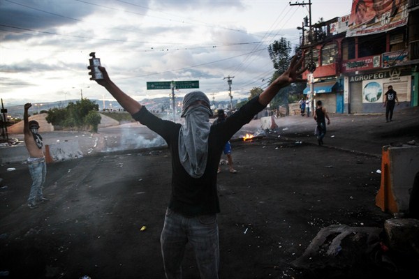A masked supporter of Honduran presidential candidate Salvador Nasralla at a roadblock set up to protest suspected election fraud, Tegucigalpa, Honduras, Dec. 1, 2017 (AP photo by Rodrigo Abd).