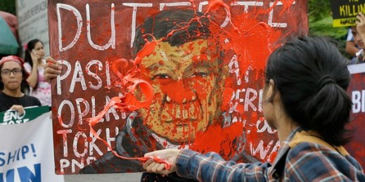 A protester splashes red paint on a picture of Philippine President Rodrigo Duterte during a rally, Manila, Philippines, Dec. 7, 2017 (AP photo by Aaron Favila).