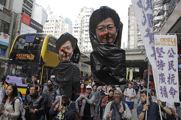 Pro-democracy protesters carry pictures of Hong Kong Chief Executive Carrie Lam during a rally, Hong Kong, Jan. 1, 2018 (AP photo by Kin Cheung).