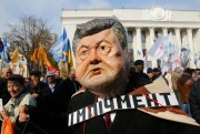 A protester wearing a mask of President Petro Poroshenko and a sign with the word "Impeachment" attends a rally outside the Ukrainian parliament, Kiev, Oct. 17, 2017 (AP photo by Efrem Lukatsky).