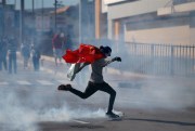 A demonstrator kicks a tear gas canister during the swearing-in of Honduran President Juan Orlando Hernandez, Tegucigalpa, Honduras, Jan. 27, 2018 (AP photo by Eduardo Verdugo).