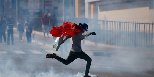 A demonstrator kicks a tear gas canister during the swearing-in of Honduran President Juan Orlando Hernandez, Tegucigalpa, Honduras, Jan. 27, 2018 (AP photo by Eduardo Verdugo).