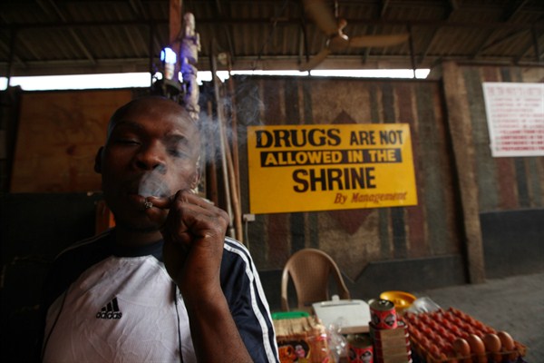 An unidentified man smokes marijuana next to a no drugs sign at the New Afrika Shrine, Lagos, Nigeria, Feb. 6, 2011 (AP photo by Sunday Alamba).