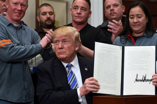 President Donald Trump holds up a proclamation on steel and aluminum imports during an event at the White House, Washington, March 8, 2018 (AP photo by Susan Walsh).