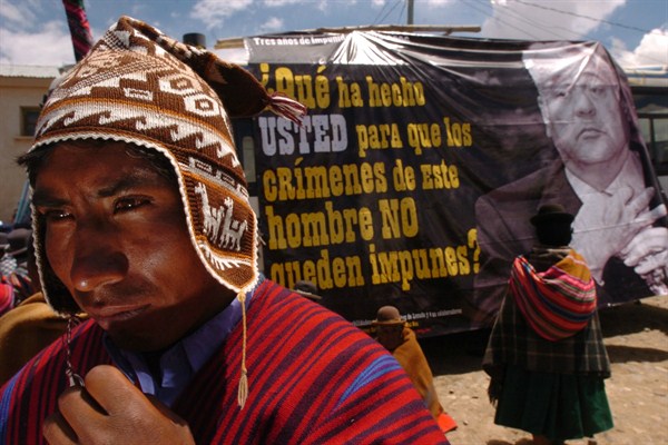An indigenous man stands in front of a banner depicting former Bolivian President Gonzalo Sanchez de Lozada, Warista, Bolivia, Sept. 20, 2006 (AP photo by Juan Karita).