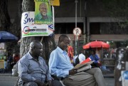 Tanzanians underneath an election poster for President John Magufuli, Dar es Salaam, Tanzania, Oct. 27, 2015 (AP photo by Khalfan Said).