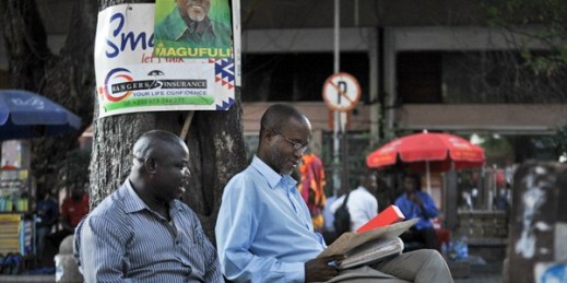 Tanzanians underneath an election poster for President John Magufuli, Dar es Salaam, Tanzania, Oct. 27, 2015 (AP photo by Khalfan Said).