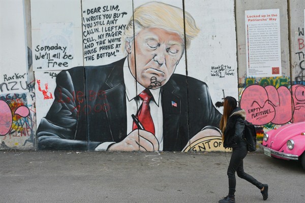 A girl walks by a mural of Donald Trump drawn on Israel’s separation barrier Bethlehem, West Bank, March 13, 2018 (Sipa photo by Artur Widak via AP).