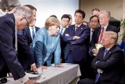 German Chancellor Angela Merkel, surrounded by other G-7 leaders, speaks with U.S. President Donald Trump during the G-7 summit, La Malbaie, Canada, June 9, 2018 (Photo by Jesco Denzel for German Federal Government via AP).