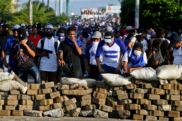 Anti-government demonstrators take cover behind a barricade after gunfire erupted during a march against Nicaraguan President Daniel Ortega, Managua, Nicaragua, May 30, 2018 (AP photo by Esteban Felix).