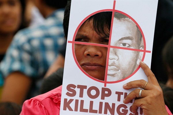 A protester displays a mock target with an image of an alleged victim of extrajudicial killings during a rally in Manila, Philippines, Dec. 10, 2017 (AP photo by Bullit Marquez).