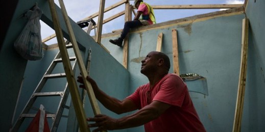 Pedro Deschamps helps workers hired by FEMA install a temporary awning roof at his house, which suffered damage during Hurricane Maria, San Juan, Puerto Rico, Nov. 15, 2017 (AP photo by Carlos Giusti).