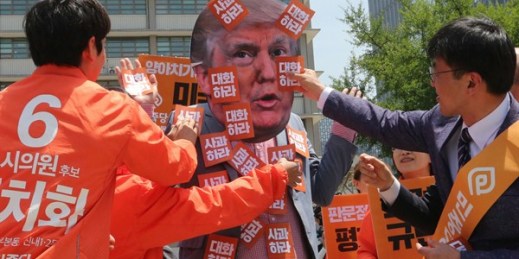 Protesters attach stickers that read “Apology” to a fellow protester wearing a mask of U.S. President Donald Trump during a rally against Washington’s handling of the North Korea issue, Seoul, South Korea, May 25, 2018 (AP photo by Ahn Young-joon).
