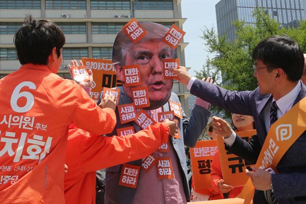 Protesters attach stickers that read “Apology” to a fellow protester wearing a mask of U.S. President Donald Trump during a rally against Washington’s handling of the North Korea issue, Seoul, South Korea, May 25, 2018 (AP photo by Ahn Young-joon).
