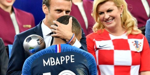 Croatian President Kolinda Grabar-Kitarovic, right, looks on as French President Emmanuel Macron kisses France’s Kylian Mbappe after France won the World Cup, Moscow, Russia, July 15, 2018 (AP photo by Martin Meissner).