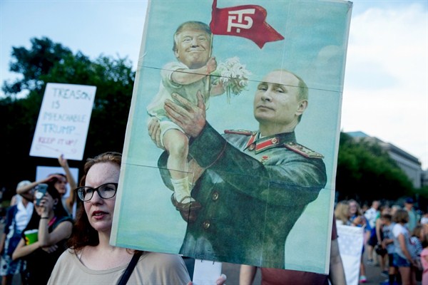 A woman holds a sign depicting Russian President Vladimir Putin and U.S. President Donald Trump during a protest outside the White House, Washington, July 17, 2018 (AP photo by Andrew Harnik).