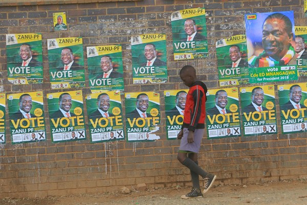 A boy walks past campaign posters for Zimbabwean President Emmerson Mnangagwa, Harare, Zimbabwe, July 25, 2018 (AP photo by Tsvangirayi Mukwazhi).