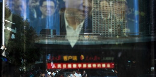 People and motorists are reflected on an electronic display panel showing video footage of Chinese President Xi Jinping near the central business district of Beijing, China, May 30, 2018 (AP photo by Andy Wong).
