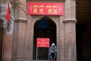 A child rests near the entrance to a mosque where a banner reads “Love the party, Love the country” in the old city district of Kashgar in western China’s Xinjiang region, Nov. 4, 2017 (AP photo by Ng Han Guan).