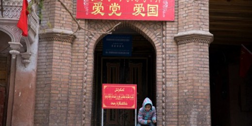 A child rests near the entrance to a mosque where a banner reads “Love the party, Love the country” in the old city district of Kashgar in western China’s Xinjiang region, Nov. 4, 2017 (AP photo by Ng Han Guan).