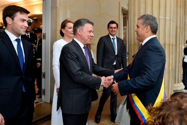 Colombia’s former president, Juan Manuel Santos, center, welcomes President Ivan Duque at the presidential palace in Bogota, Colombia, Aug. 7, 2018 (Colombia’s presidential press office via AP).