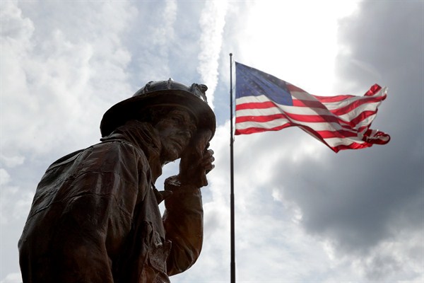 A statue depicting a New York City firefighter wiping sweat from his forehead stands at a display honoring first responders to the 9/11 attacks, Buffalo, N.Y., Aug. 10, 2018 (AP photo by Julio Cortez).