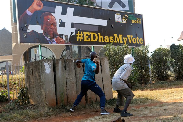An opposition party supporter throws a rock aimed at a campaign poster for Zimbabwean President Emmerson Mnangagwa, Harare, Zimbabwe, Aug. 1, 2018 (AP photo by Tsvangirayi Mukwazhi).