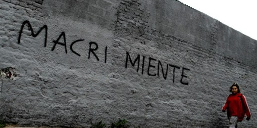 A woman walks past a wall spray painted with a message that reads in Spanish “Macri lies”, Buenos Aires, Argentina, Aug. 30, 2018 (AP photo by Natacha Pisarenko).