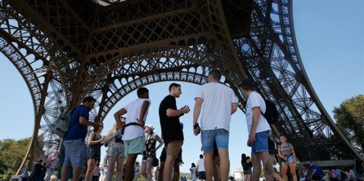 Tourists stand under the Eiffel Tower in Paris, Aug. 2, 2018 (AP photo by Michel Euler).