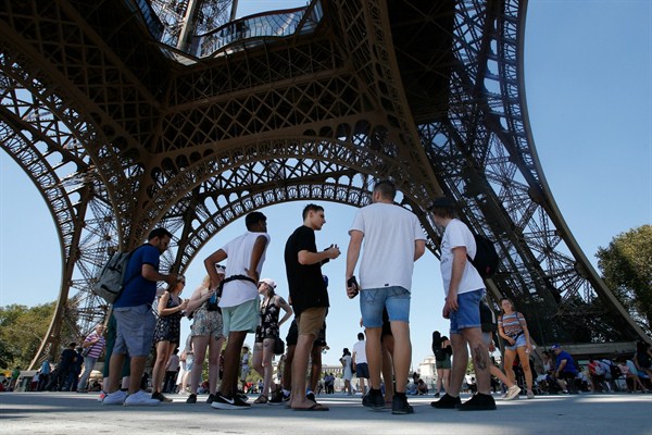 Tourists stand under the Eiffel Tower in Paris, Aug. 2, 2018 (AP photo by Michel Euler).