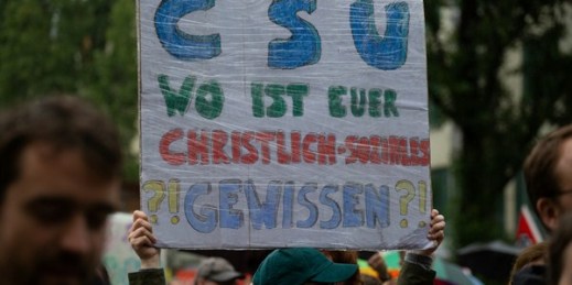 A protester holds a sign that reads, “CSU where is your Christian-social conscience?”, Munich, Germany, July 22, 2018 (Photo by Alexander Pohl for Sipa USA via AP Images).