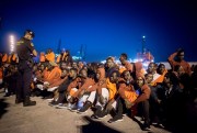 Migrants sit in front of Spanish police officers at the port of Algeciras, southern Spain, July 31, 2018 (AP photo by Marcos Moreno).