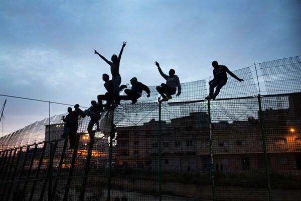 Migrants from sub-Saharan Africa climb over a fence that divides Morocco and the Spanish enclave of Melilla, March 28, 2014 (AP photo by Santi Palacios).