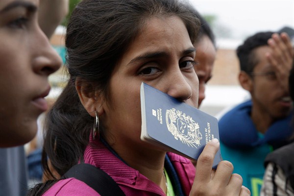 A Venezuelan migrant holds her passport while waiting in line for a bus in Tumbes, Peru, Aug. 25, 2018 (AP photo by Martin Mejia).